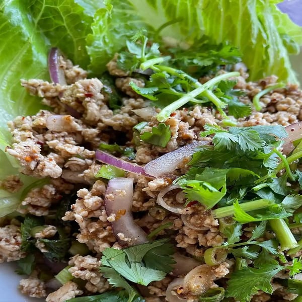 Close-up of Thai Larb Gai with minced chicken, red onion, and cilantro in a lettuce cup.