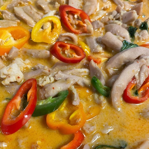 Close-up of Thai green curry with chicken, red, yellow, and green bell peppers.